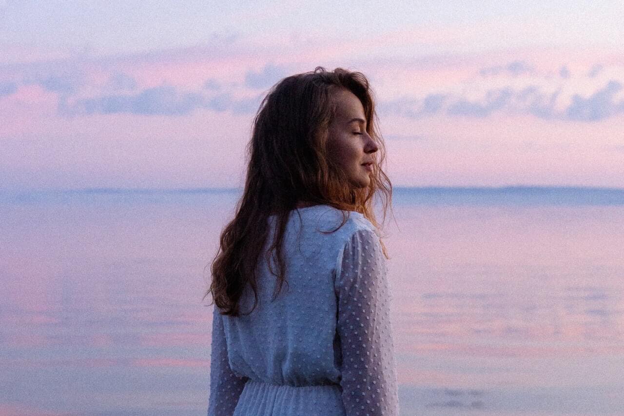 Woman standing in the ocean at sunset
