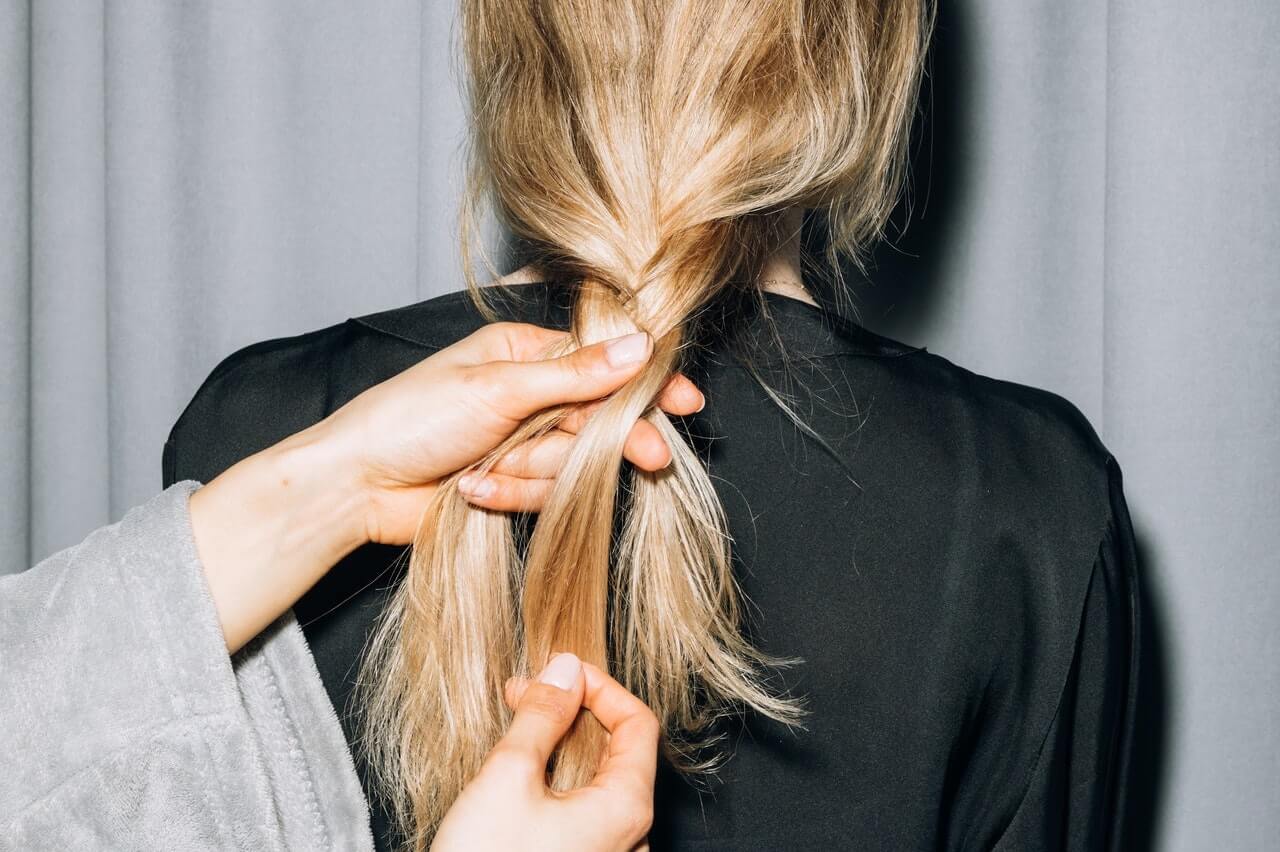 blonde woman getting her hair braided