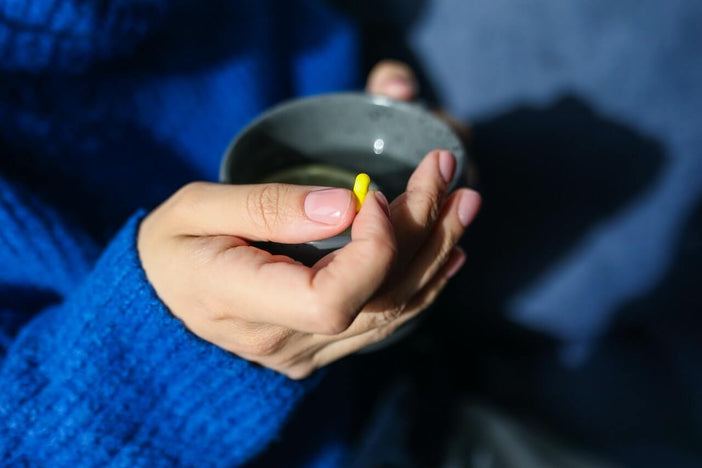 Person holding pill and tea
