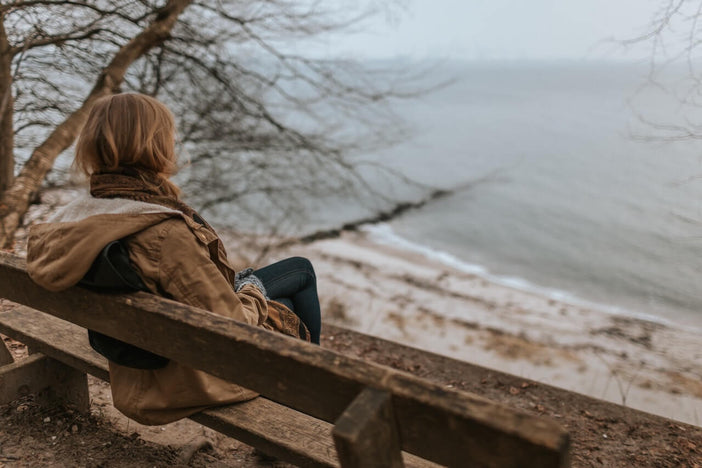Woman sitting on bench looking at the ocean