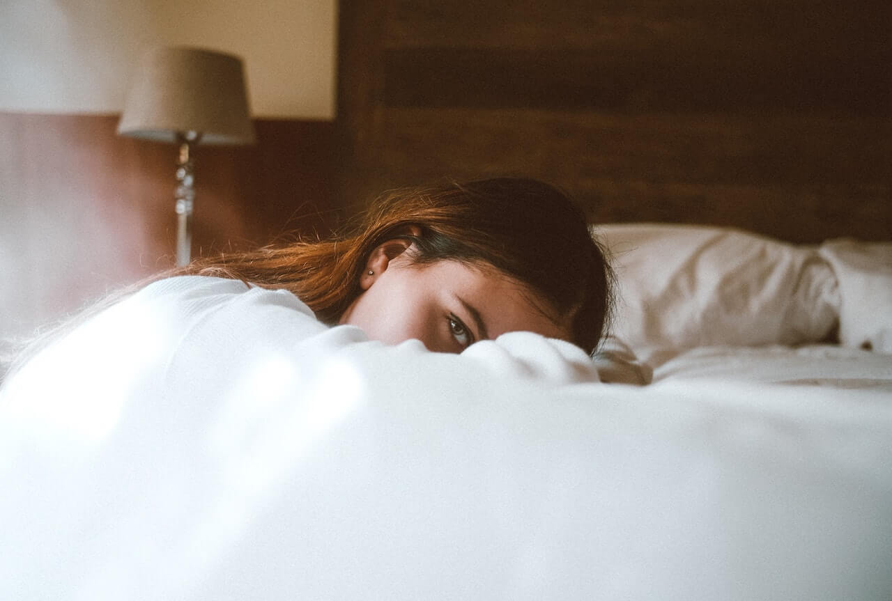 Woman with brow hair resting on a bed 