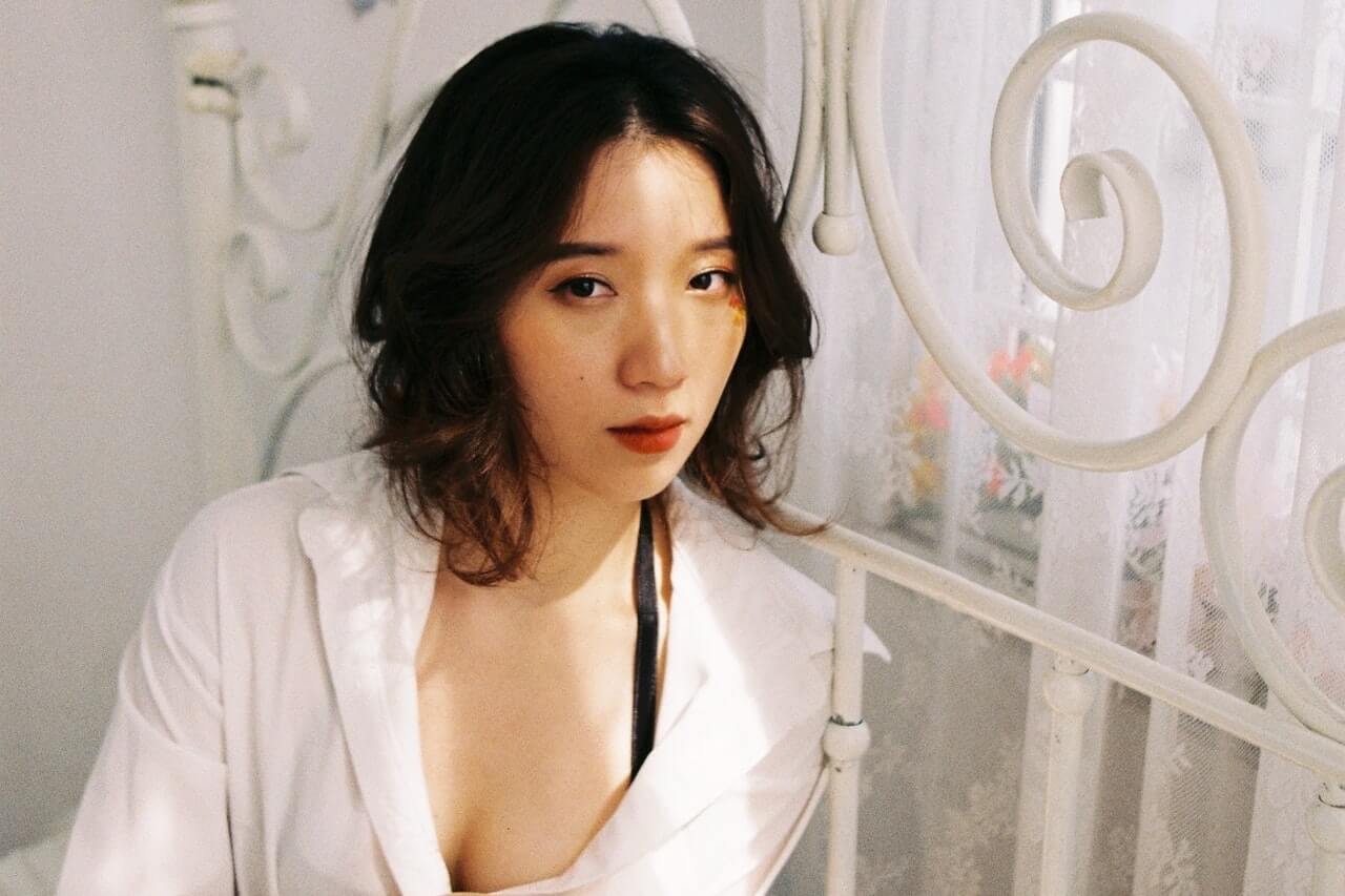 Woman with brown hair sitting on a bed