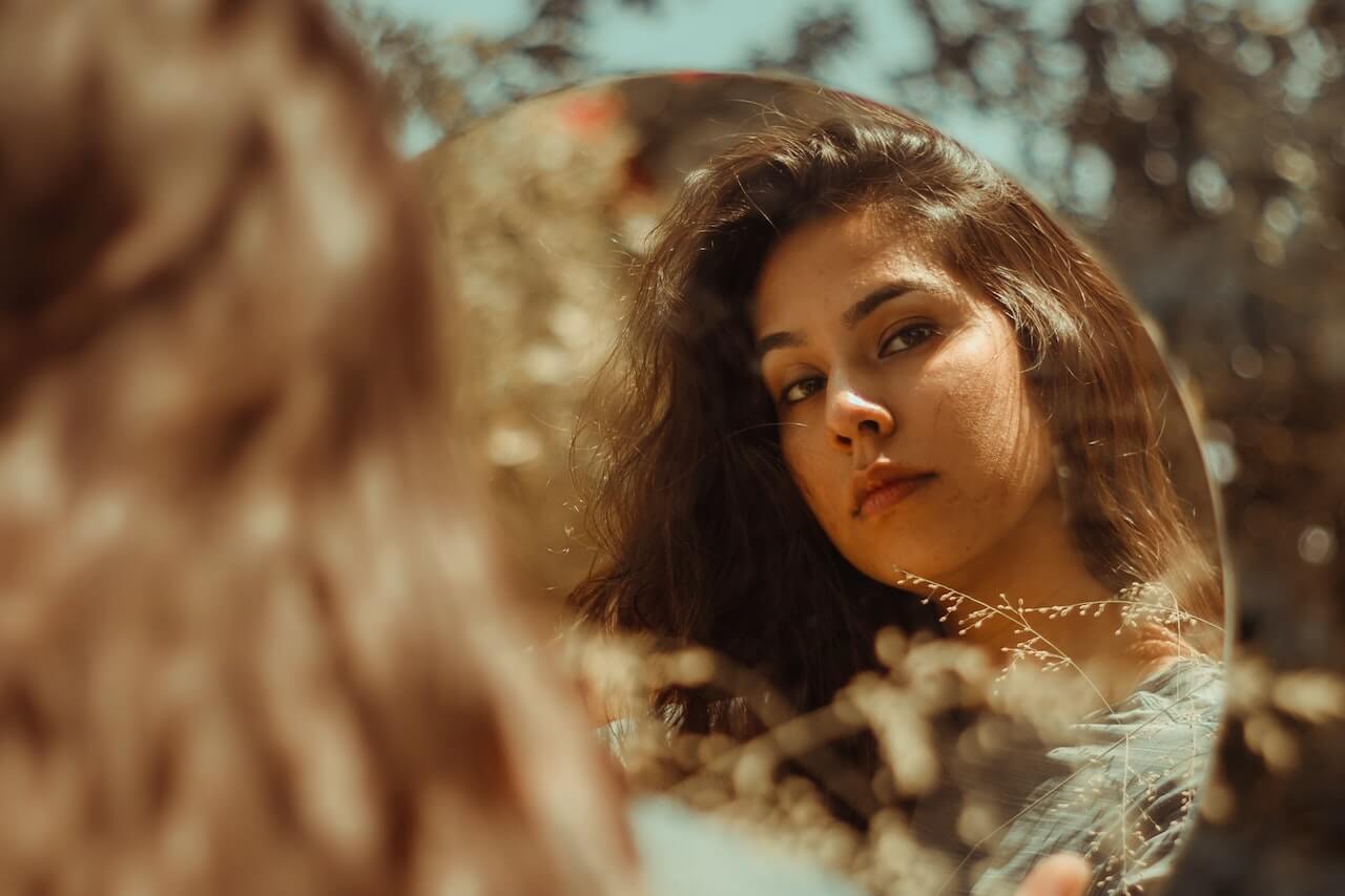 Woman with brown hair looking in the mirror