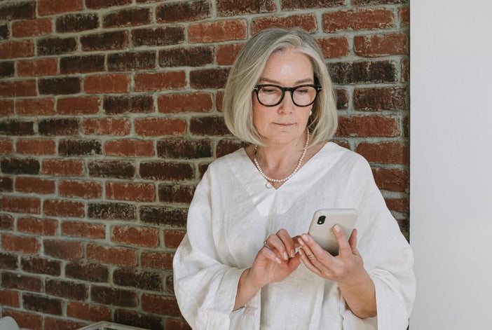Woman with gray hair and glasses looking at her phone