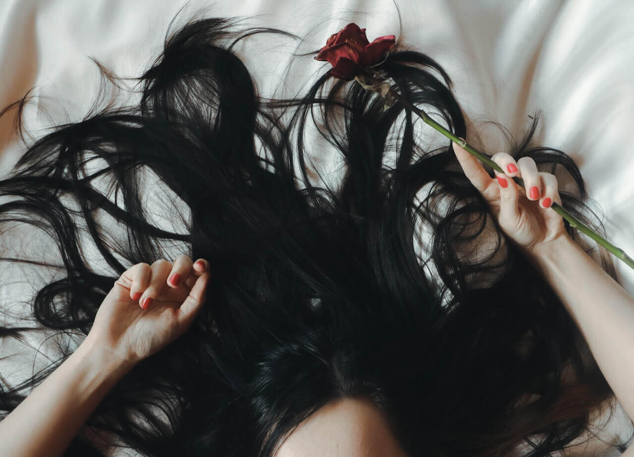 Woman with black hair holding a rose