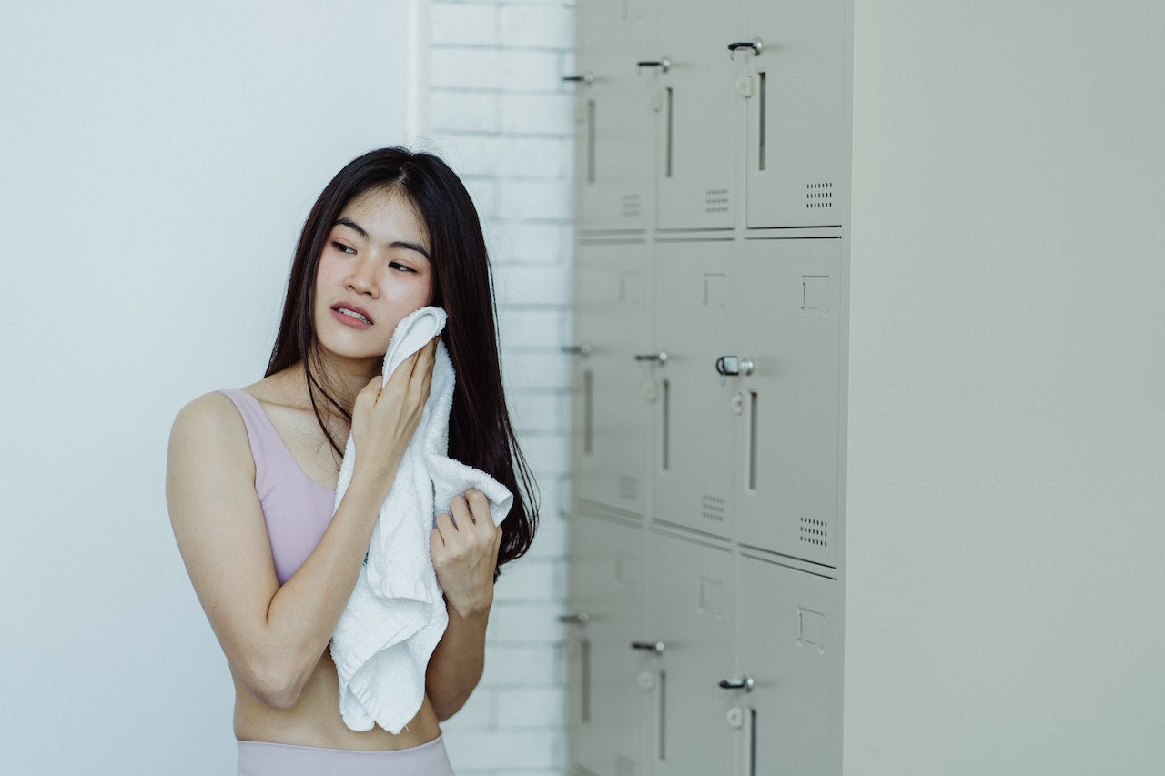 Woman using towel to wipe away sweat in the gym