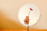 Hand holding flower in mirror