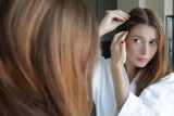 Woman examining scalp in mirror