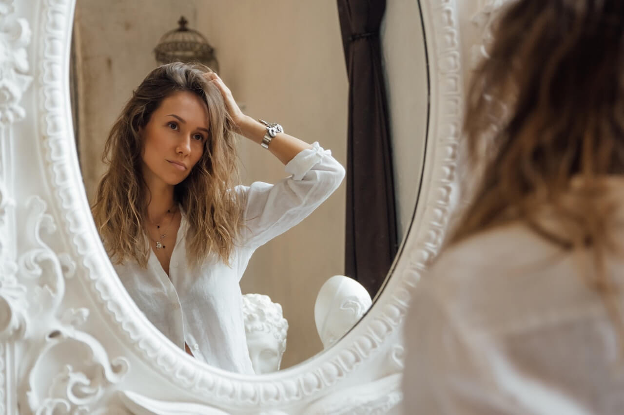 Woman looking at hair in mirror